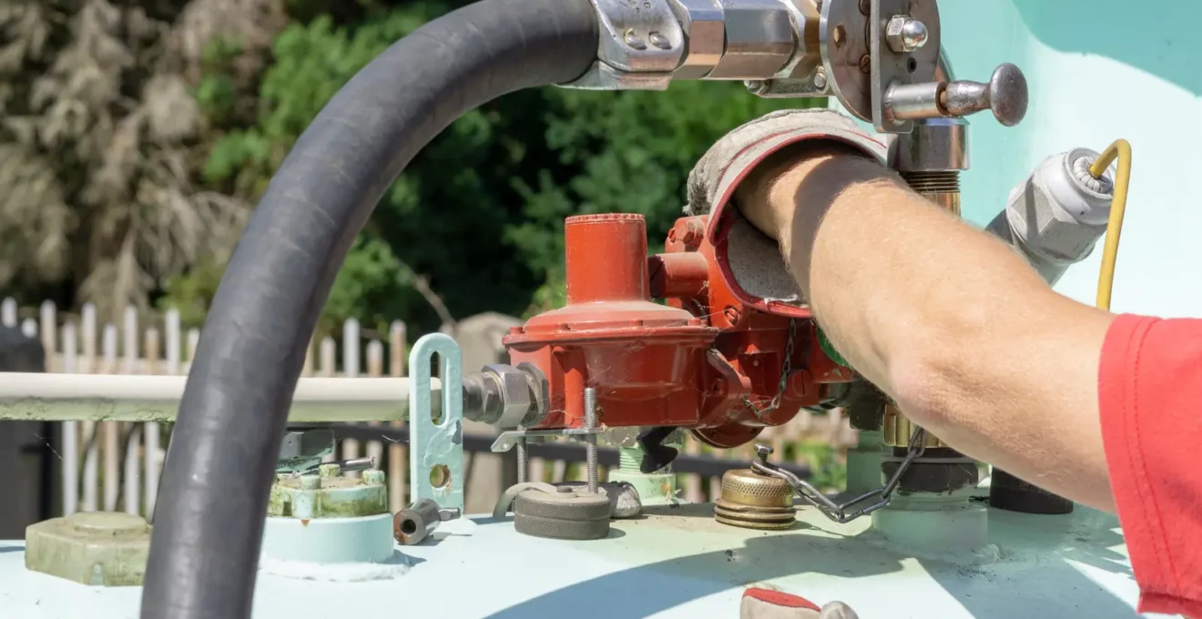 Technicien utilisant une clé pour intervenir sur les raccordements et vannes d'une citerne de gaz propane