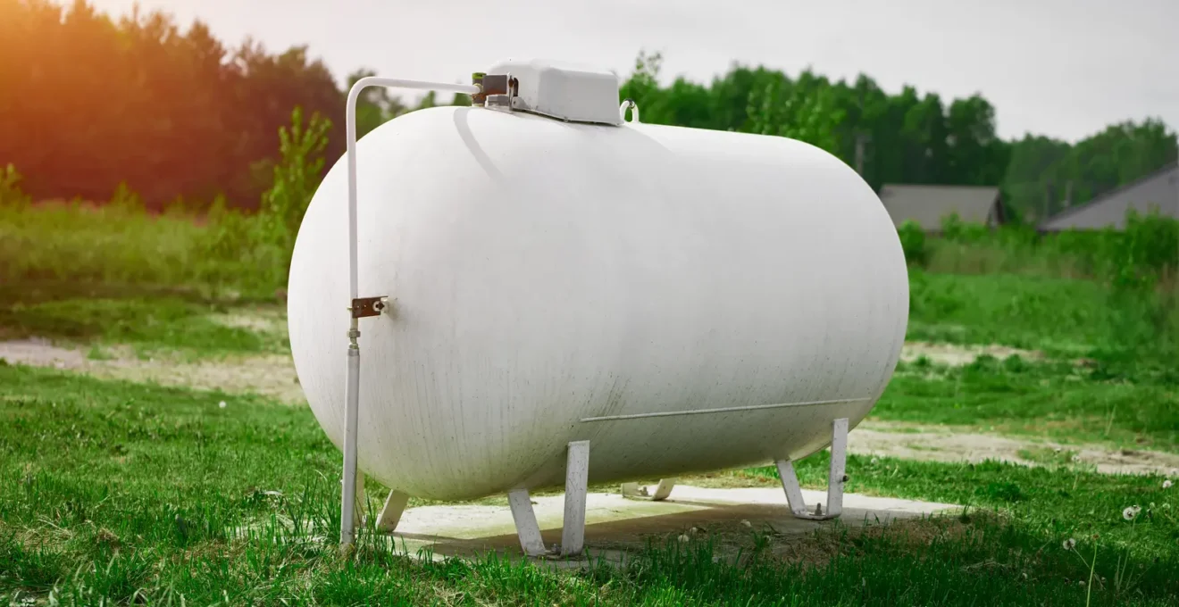 Technicien professionnel inspectant une citerne de gaz propane aérienne installée dans le jardin d'une maison individuelle française