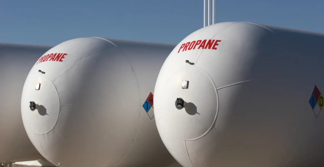 Mains d'un technicien examinant la plaque d'identification technique sur une citerne de gaz propane